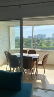 a dining room with a table and chairs and a window at Unité dans un complexe prestigieux Marina Golf in Settat