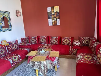 a living room with a red couch and a table at Ferme touristique domaine BENJDYA à HAD SOUALEM in Berrechid