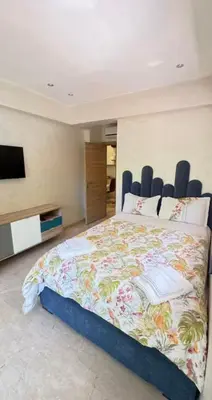 a bedroom with a large bed and a tv at appartement de luxe au rez de jardin avec piscine privative in Tamaris