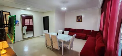 a living room with a table and a red couch at Appartement à côté de mosquée Hassan 2 et marina shopping in Casablanca
