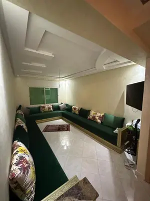 a living room with a green couch and a tv at Appartement sidi rehal in Casablanca