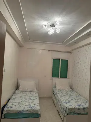 two beds in a room with two green windows at Appartement sidi rehal in Casablanca
