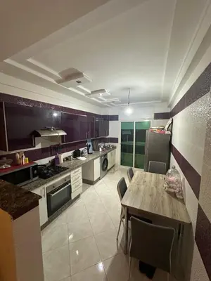 a large kitchen with a wooden table and chairs at Appartement sidi rehal in Casablanca
