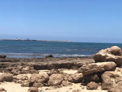 a beach with rocks and the ocean in the background at Chambre cosy en bord de mer in Mohammedia