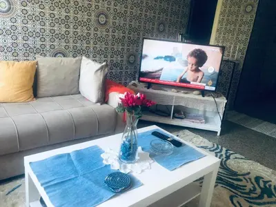 a living room with a couch and a table with a tv at Chambre cosy en bord de mer in Mohammedia