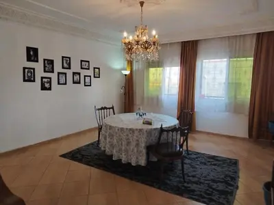 a dining room with a table and chairs and a chandelier at Appartement aéroport Mohammed 5 in Deroua