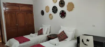 a room with two beds and clocks on the wall at Appartement aéroport Mohammed 5 in Deroua