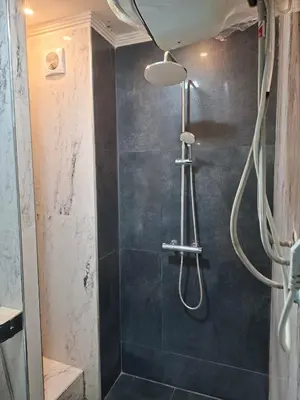 a bathroom with a shower with a blue wall at Appartement vu sur Mer in Mohammedia
