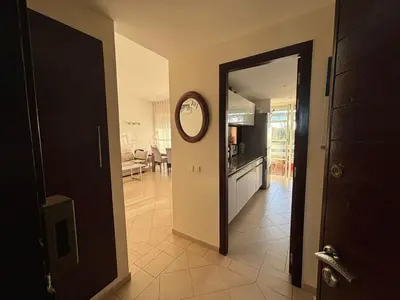 a hallway leading to a kitchen with a clock on the wall at Appartement Bouznika Bay Golf Beach in Bouznika