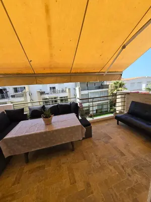 a patio with a table and couches on a balcony at Les perle de tamaris in Dar Mohammed Ould Haj Jilali