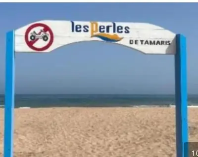 a sign on a beach with the words las batteries at Les perle de tamaris in Dar Mohammed Ould Haj Jilali