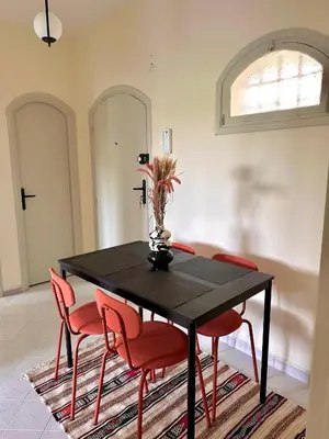 a dining room with a black table and red chairs at Cozy Stay with Hassan Tower View in Rabat