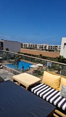 a balcony with a couch and a swimming pool at Blue Beach Residence Balnéaire pour familles in Sidi Rahal