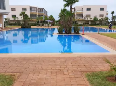 a swimming pool in a resort with blue water at Blue Beach Residence Balnéaire pour familles in Sidi Rahal