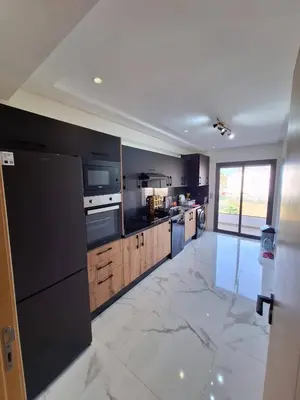 a large kitchen with black appliances and a marble floor at Sidi Rahal Appt raffiné, pieds dans l'eau in Sidi Rahal