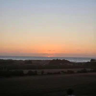 a sunset over the ocean with a field at Appartement Moderne très bien équipé pour familles seulement- Résidence Garden Bay Dar Bouazza in Tamaris