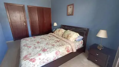a bedroom with a bed and a table with a lamp at Appartement moderne proche de la plage avec piscine in Skhirat