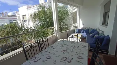 a balcony with a table and chairs and a couch at Appartement moderne proche de la plage avec piscine in Skhirat