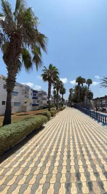 a cobblestone road with palm trees and buildings at Séjour cosy à Palm Beach Mansouriah in Pont Blondin