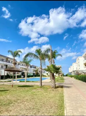 a resort with palm trees and a swimming pool at Appartement à 10min de la mer in Mansouria
