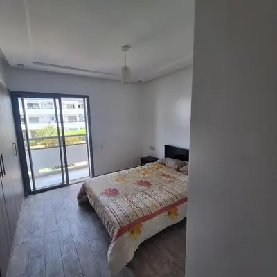 a bedroom with a bed and a large window at Appartement à 10min de la mer in Mansouria