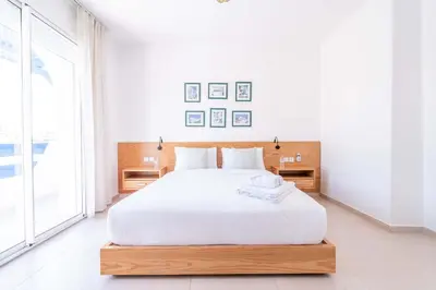 a white bedroom with a large bed and a large window at Villa in Golf Resort with Shared Pool in Bouznika