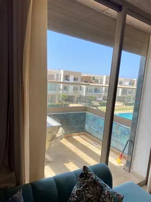 a living room with a view of a pool from a window at Appartement dans une résidence fermée, Malaga Beach in Mohammedia