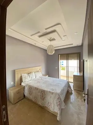 a bedroom with a large bed and a ceiling at Appartement dans une résidence fermée, Malaga Beach in Mohammedia