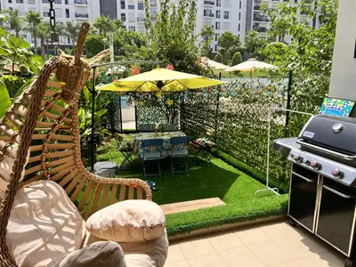 a patio with chairs and an umbrella and a grill at Logement 5 etoiles avec piscine et jardin privée à rabat hay riad in Rabat