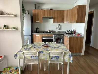 a kitchen with a table and chairs and a kitchen with a stove at Appartement vue piscine - Pour Famille - Blue Beach SIDI RAHAL in Sidi Rahal
