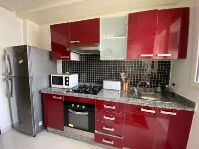 a kitchen with red cabinets and a stainless steel refrigerator at Appartement deux chambre confortable près de la Gare - Restau - cafes - Plage in Casablanca