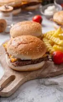 a sandwich on a wooden board with french fries at KHaIMA