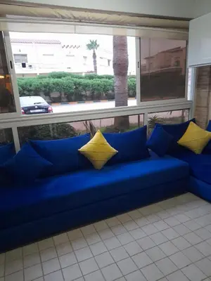 a blue couch with yellow pillows in front of a window at La cascade 2 in Sidi Rahal