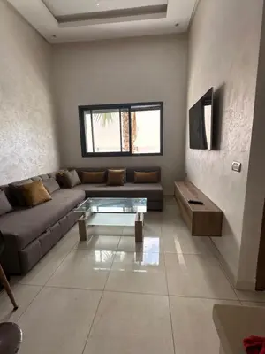a living room with a couch and a glass table at Appartement calme in Bouznika