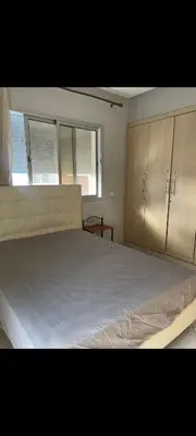 a bedroom with a large bed and two windows at Sidi rahal apartment in Sidi Rahal