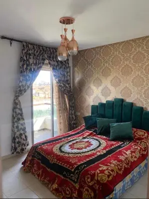 a bedroom with a bed with a red blanket and a window at Puerto banus in Mansouria