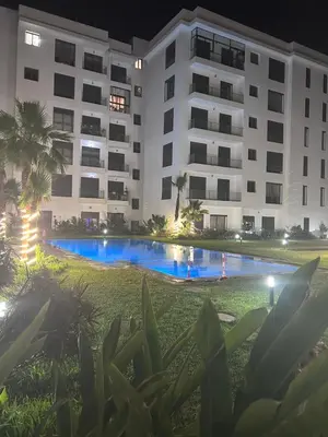 a building with a swimming pool in front of a building at Appartement élégant et raffiné in Nouaseur