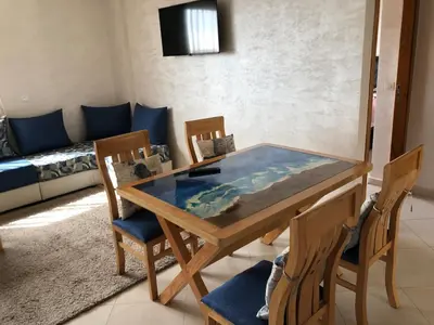 a dining table with a glass top in a living room at Sable d or in O Ben Slimane