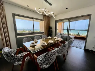 a dining room with a table and chairs and windows at ghaouat luxury appart in Casablanca