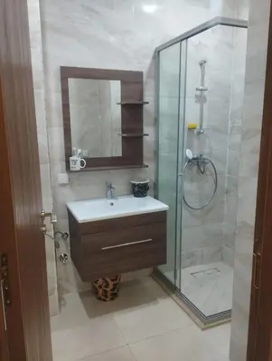 a bathroom with a sink and a glass shower at Appartement à louer à Bouznika avec piscine in Bouznika