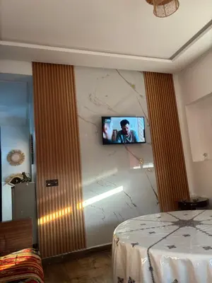 a room with a tv on a wall with a bed at Cozy apartment near the airport in Deroua