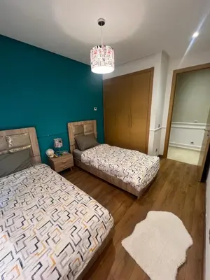 a bedroom with two beds and a chandelier at Appartement Élégance Cosy in Rabat
