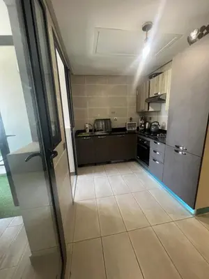 a kitchen with black cabinets and a tile floor at Appartement Élégance Cosy in Rabat