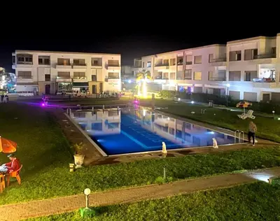 a swimming pool in front of a building at night at Mohmmadia puerto banus in Mohammedia
