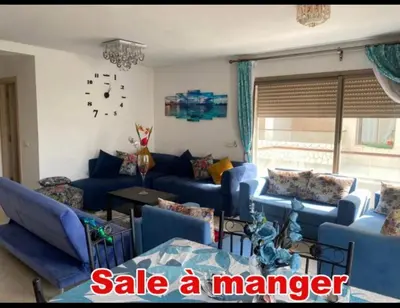 a living room with blue couches and a clock on the wall at Mohmmadia puerto banus in Mohammedia