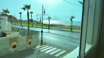 a view of a street with palm trees and the ocean at Immense appartement familial vue sur mer in Rabat