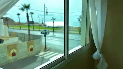 a window with a view of a street with palm trees at Immense appartement familial vue sur mer in Rabat