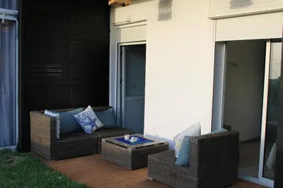 a patio with two wicker chairs and a table at K Playa Vibe Darbouazza in Dar Bouazza