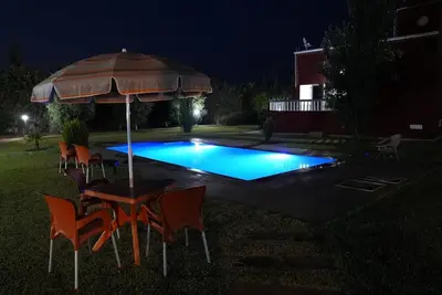 a table with an umbrella next to a swimming pool at night at Farm Fields and Forests 20 min from carrefour berchid in Berrechid