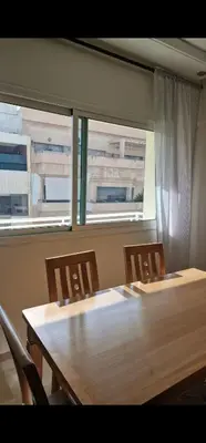 a table and chairs in a room with two windows at Appartement cosy près Abdelmoumen Maarif in Casablanca